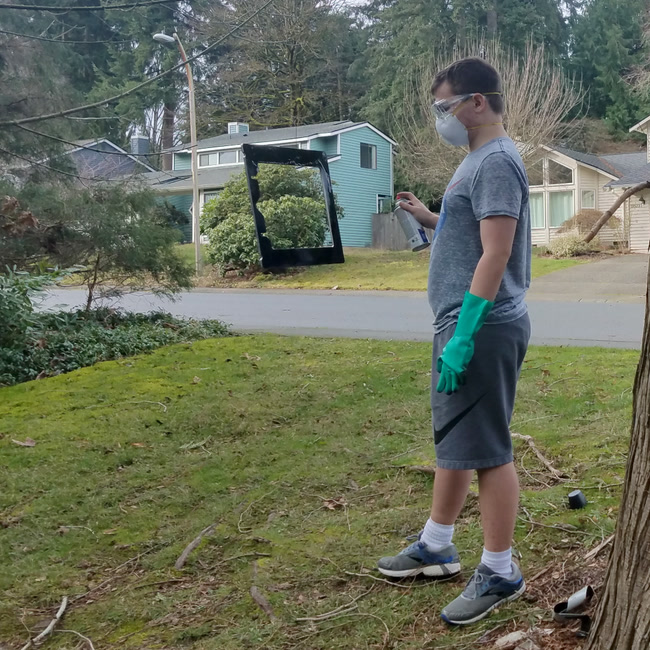 Painting the aluminum frame hanging from a tree.